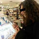 Una ragazza intenta a scegliere il tester di un rossetto in profumeria. Il tester � una confezione del cosmetico messa a disposizione del cliente per una prova